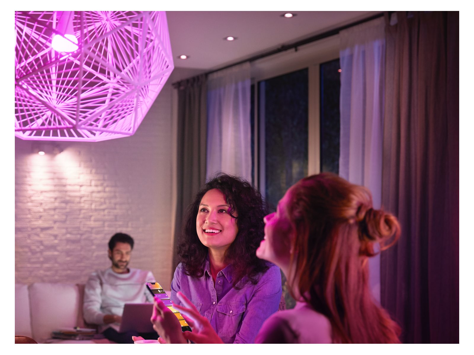 A close up of peoples faces sitting under a violet light