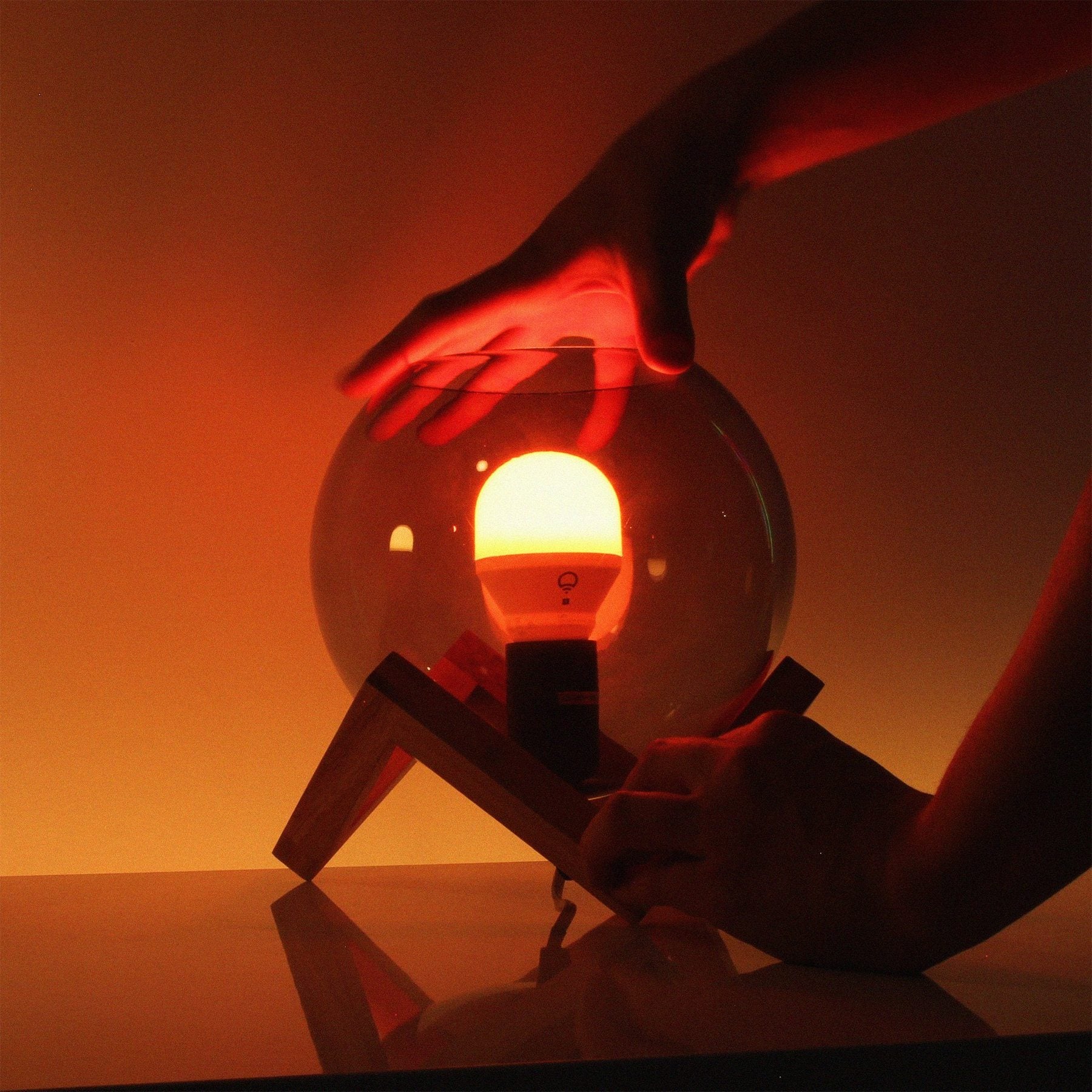 a person holding a warm amber light coming from a lamp 