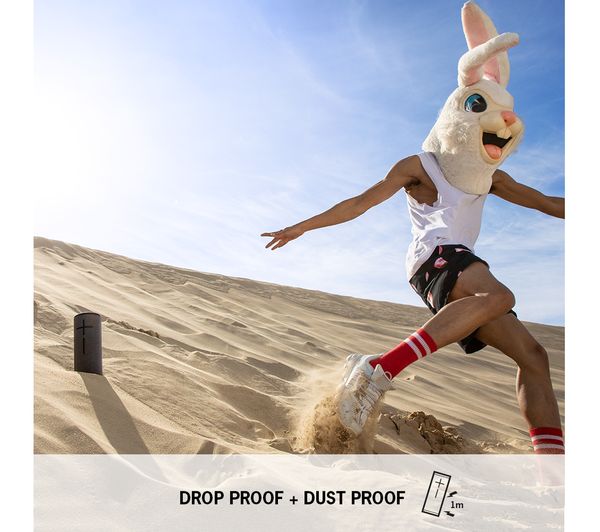 a person running down a sand dune with a rabbit head costume and speaker in the sand