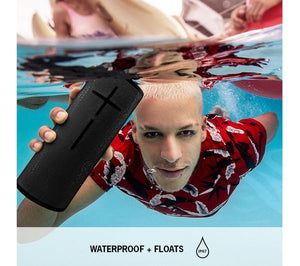 a person in a red shirt underwater holding the logitech ultimate ears boom 3 speaker underwater