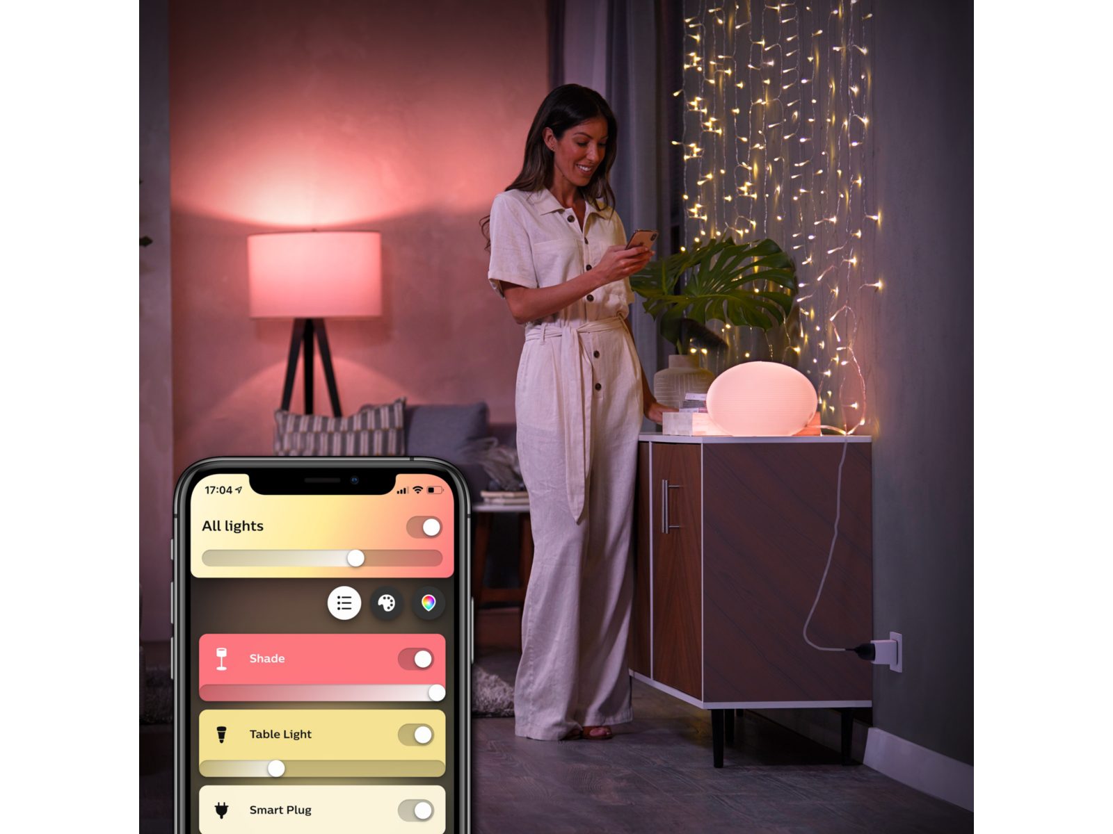 person using a mobile phone to control the lights and an inset image of the mobile phone screen showing the Hue app