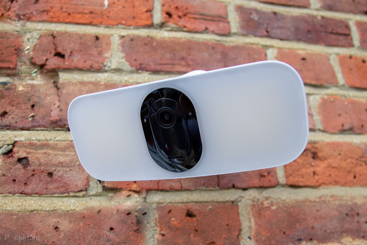 An arlo pro 3 smart flood light mounted on a brick wall 