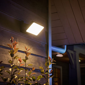 The philips hue discover flood light shining with a bright white light.  It is attached to a wooden building