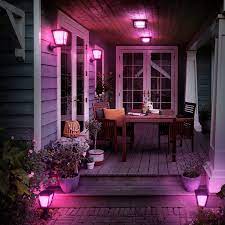 A porch with several philips hue econic wall lanterns shining a pink light.