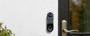 An Arlo Wire Free Video Doorbell mounted on a white wall with sound marks emanating from the speaker