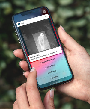 A mobile phone showing the arlo app sending the user a motion detection alert with a video capture of a suspicious looking person 